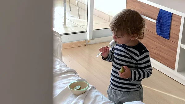 小さな幼児男の子食べるキウイフルーツとともにスプーン — ストック写真