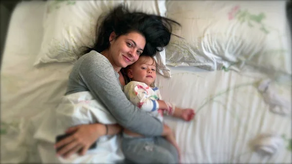 お母さんと赤ちゃんが一緒にベッドに横たわっこんにちは手を振る 幼児男の子とお母さん抱っこ — ストック写真
