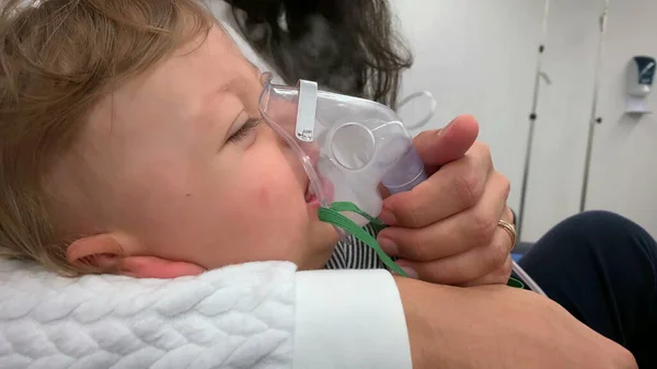 Mother giving inhaler to baby toddler boy with respiratory problems