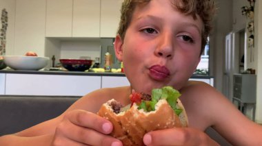 Hamburger yiyen genç bir çocuk. Hamburger yiyen çocuk.