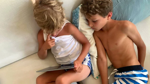 Två Unga Pojkar Tittar Medieinnehåll Surfplattan Sittandes Soffan Hemma — Stockfoto