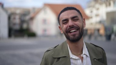 Gülen ve gülümseyen mutlu bir Orta Doğulu. Otantik gerçek hayat, şehrin dışında duran Arap bir erkeğin gülüşü ve gülüşü.
