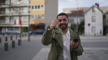 Bir Arap, şehirde kameraya bakarken başarıyı kutluyor. Mutlu Faslı insan yumruğuyla alkışlıyor.