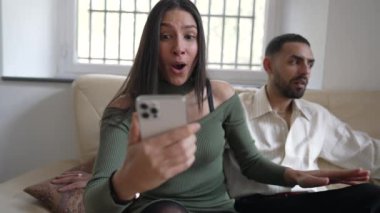 Heyecanlı kız arkadaş cep telefonundan sevgilisine olumlu haberler veriyor. Mutlu çift, telefon tutarken başarılı bildirim mesajını kutluyor