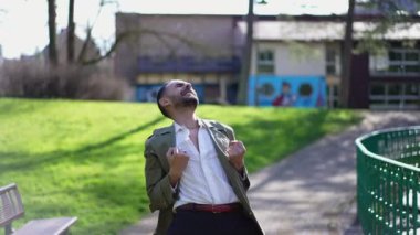 Mutlu bir Orta Doğulu adam güneşli bir günde parkta başarıyı kutluyor. Neşeli bir Arap erkeği kendinden geçmiş hissediyor.