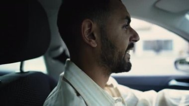 Orta Doğulu mutlu bir adam araba kullanıyor. Gülümseyen bir erkek sürücünün iç perspektifi, profil yakın çekim yüzü