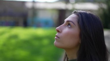 Düşüncelere dalmış genç bir kadının gülümseyerek gözlerini açması... Umutla ve inançla parkın dışında dururken...