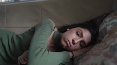 Yorgun bir kadın uzun bir günün ardından kanepede dinleniyor. 20 'li yaşlarda yorgun ve stresli bir günün ardından dinlenen yetişkin bir kız.