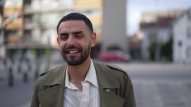 Orta Doğulu mutlu bir genç adam şehrin sokaklarında kendine güvenle gülümsüyor. Arap bir erkeğin portresi