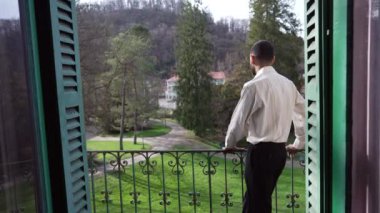 Evinin balkonunda durmuş bahçeye bakan düşünceli bir delikanlının arkasında. Düşünceli bir insanın lüks yaşam tarzı.