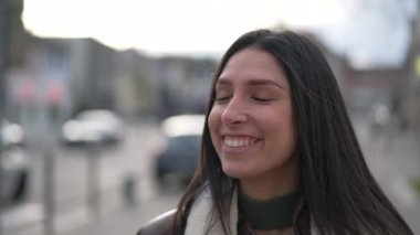 Genç, kendine güvenen esmer bir kadının portresi kameraya doğru gülümseyerek yürüyor. Mutlu, yetişkin bir kız. Sokakta ağır çekimde yakın çekim yüzü.