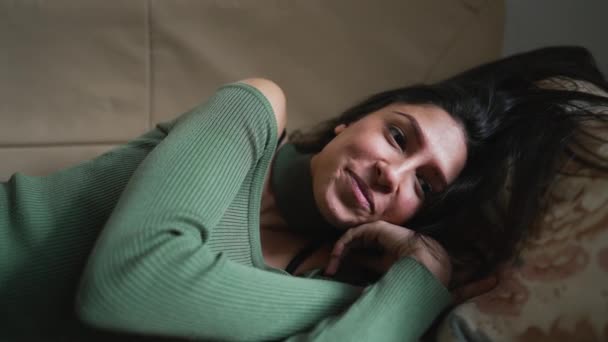 一位中东的年轻女子一边躺在沙发上一边放松 一边咧嘴笑着 一个20多岁的阿拉伯成年女孩在休息 — 图库视频影像