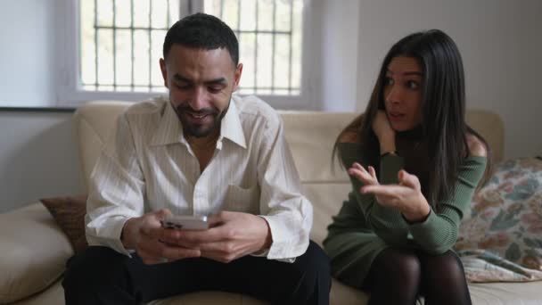ガールフレンドが自宅のソファで無視されているように感じる間 男は電話で夢中になりました 中東アラブ人のカップル — ストック動画