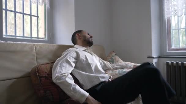 一天的工作结束后 一个中东人坐在沙发上解闷 一个精疲力尽后放松的阿拉伯人 — 图库视频影像