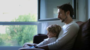 İçeride koltukta oturan samimi baba ve oğul. Yaşam tarzı otantik gerçek baba ve çocuk ilişkisi. Çocuk babasının kucağına oturdu.