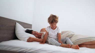 Anne ve çocuk sabah kalktığında yatakta yatıyorlar. Küçük çocuk güne başlayarak yataktan kalkıyor. Aile anneliği yaşam tarzı