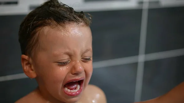 洗澡时 一个哭哭啼啼的小男孩在淋浴间里很不高兴 洗发水使小男孩的卫生习惯烦躁不安 — 图库照片