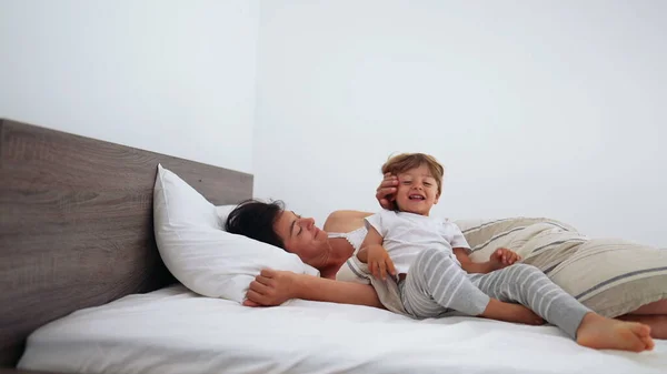 stock image Mother and child laying in bed in the morning waking up. Little boy getting out of bed starting the day. Family motherhood lifestyle