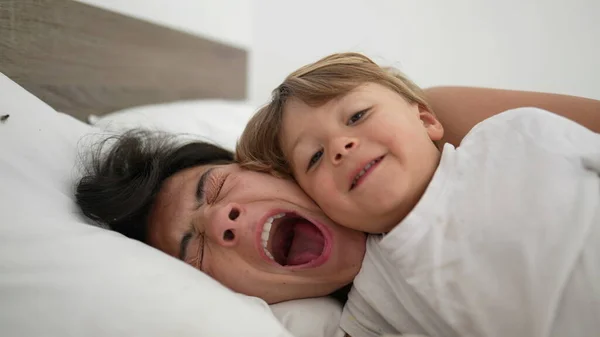 妈妈在床上打呵欠 早上醒来 带着孩子 厌倦了母亲的生活方式概念 妈妈打呵欠躺在床上 真实和真实 — 图库照片