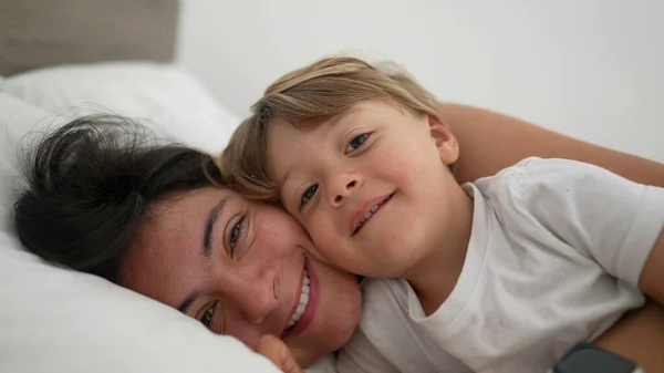 엄마와 아이가 침대에 누워서 카메라를 있습니다 어머니라는 개념은 소년의 맞대는 — 스톡 사진