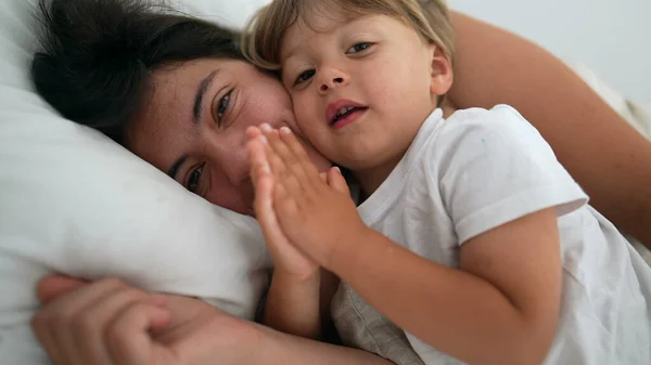 母親と子供の息子のベッドで一緒に本物の現実の生活の瞬間に横たわっている 母なる愛と愛情と子供との朝の週末 — ストック写真