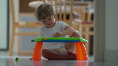 Küçük çocuk evdeki manyetik silinebilen tahtalarla oynuyor. Çocukluk yaşam tarzı gelişimi. Çocukların kendi başlarına oynamayı öğrendikleri gizli bir sahne.