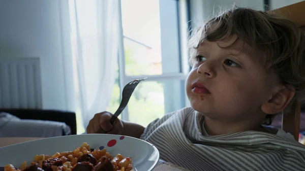 stock image One cute small boy eating lunch by himself with fork. Child eats pasta. Authentic family lifestyle at home during meal time