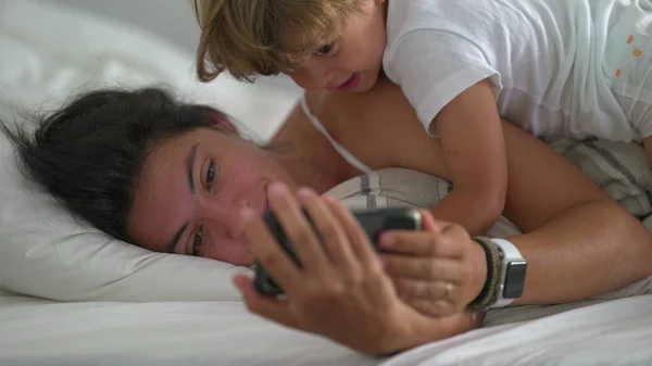 엄마와 아이가 아침에 침대에서 전화를 있습니다 아침에 스마트폰으로 엄마의 관심을 — 스톡 사진