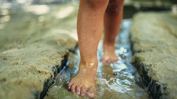 Kid feet stepping in wet muddy sand barefoot. Child closeup foot walking in sand at park outdoors. Childhood lifestyle