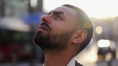 Ortadoğulu bir erkek sokak çocuğu, derin ve düşünceli bir ifadeyle gökyüzüne bakıyor. Kamera şüphelinin yüzüne odaklanmış durumda. Meditasyon durumunu ve çevre kentsel çevreyi yakalıyor..
