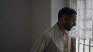 Düşünceli genç bir Arap nöbet tutarken pencerenin kenarında bekliyor. Düşünceli bir Orta Doğulu erkek.