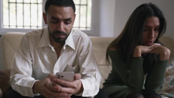 彼女は自宅でソファに座って無視感じている間 中東の男は ソーシャルメディアが電話を保持して催眠状態に ひとつのコンセプト — ストック動画
