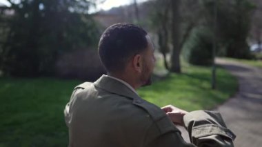 Mutlu, kendinden emin bir Arap parkın dışında yürüyüp gün ışığının ve temiz havanın tadını çıkarıyor. Orta Doğulu bir insanın gülümsemesi ve tasasız kalmasının görüntüsü.