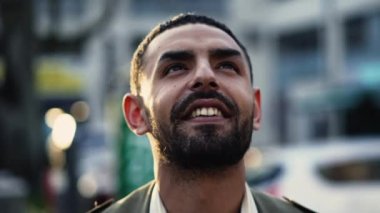 Bir şehir caddesinde durup yüzünde mutlu ve umut dolu bir ifadeyle gökyüzüne bakan Arap kökenli bir adam. Öznenin yüzüne yakın çekim yaparak, olumlu duygularını ve arka plandaki kentsel çevreyi yakalıyor.