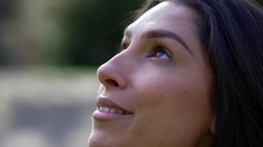 Genç bir kadın sadık bir ifadeyle gökyüzüne bakıyor. Yetişkin bir kızın gökyüzüne bakarken umutla gülümsemesi mutluluk konsepti.