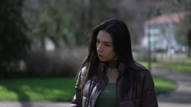 Güneş ışığı ve temiz havada parkta yürüyen tefekkür eden esmer bir genç kadın. 20 'li yaşlarda düşünceli yetişkin bir kız dışarı çıkıyor.