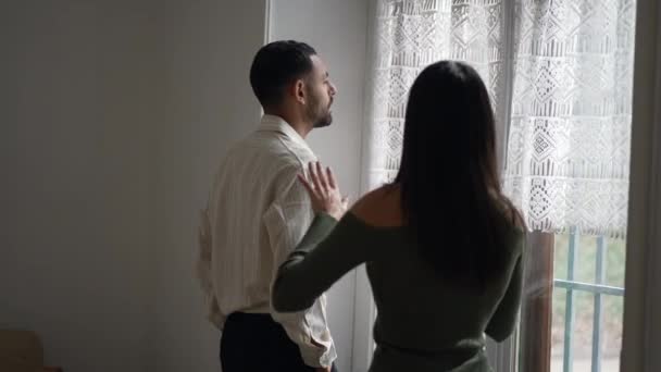 男朋友沉默寡言 而女友则取笑他沉着镇定的举止 女人背后对站在窗边的男人做手势 — 图库视频影像