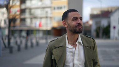 Orta Doğulu mutlu bir genç adam şehrin sokaklarında kendine güvenle gülümsüyor. Arap bir erkeğin portresi