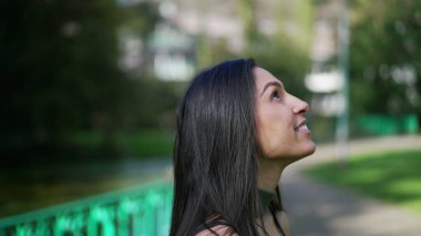 Orta Doğulu gülümseyen genç bir kadın gökyüzüne bakıp minnettarlık duyuyor.