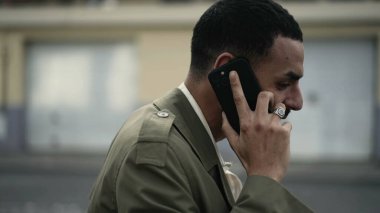 Şehir sokağında bir Arap telefonda konuşuyor. Orta Doğulu bir erkek kulağına akıllı telefon cihazı dayamış.