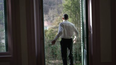 Geniş pencereler açan, balkona çıkan, temiz havanın tadını çıkaran ve düşüncelere dalmış birinin arka planı.