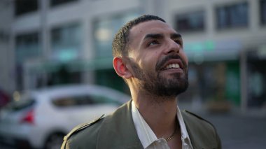 Şehirli bir Fas 'lı genç adam, mutlu bir ifadeyle UMUT ve FAITH ile gökyüzüne bakıyor. Bir Arap Orta Doğulu erkek. Yakın çekim yüzü.