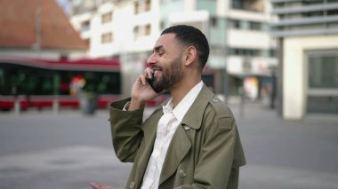 Orta Doğulu mutlu bir genç adam şehrin sokaklarında kendine güvenle gülümsüyor. Arap bir erkeğin portresi