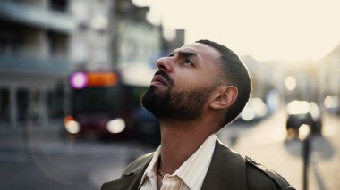 Sokakta durup gökyüzüne bakan meditasyon yapan genç bir Arap ruhani bir deneyim yaşıyor. Orta Doğulu bir erkeğin yakın plan yüzü şehir ortamında izleme çekiminde dışarıda duruyor.