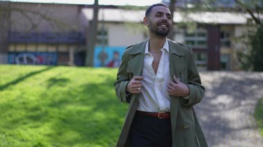 Orta Doğulu bir adam parkta başarıyı sevinçle atlayarak kutluyor. Coşkulu, mutlu bir Arap.