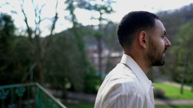 Düşünceli genç bir Orta Doğulu balkonun önünde dikiliyor. Düşüncelere dalmış. Düşünceli bir Arap erkeği hayatı yakından düşünür.