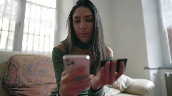 スマートフォンを使って自宅に座っている間にクレジットカード情報を追加する製品をオンラインで購入する女性 デジタル購入をする若い人 — ストック写真
