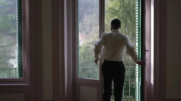 stock image Back view of person opening large windows and stepping out to home balcony enjoying fresh air and standing in contemplation