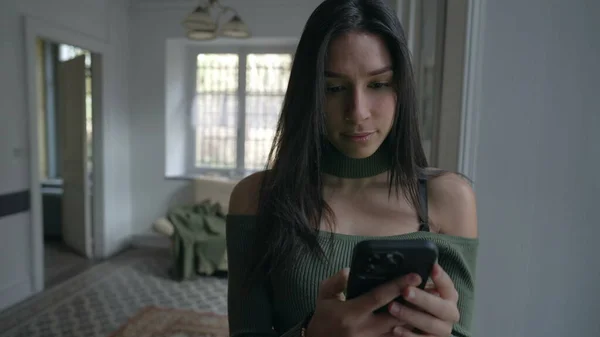 여자는 전화기를 스크린을 보면서 집에서 창문으로 집안에 있었다 기술을 사용하는 — 스톡 사진