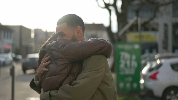 Two friends hug and embrace outside, real life happiness reunion. A middle Eastern male and female friend hugging each other in city street. Tracking shot